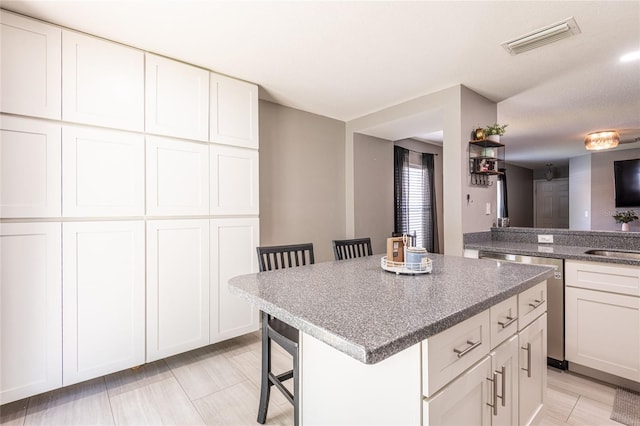 4132 Festival Pointe Blvd, Mulberry, FL 33860 - kitchen with stainless steel dishwasher, a kitchen island, a kitchen breakfast bar, and white cabinetry