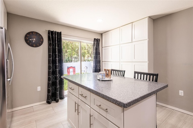 4132 Festival Pointe Blvd, Mulberry, FL 33860 - kitchen with stainless steel fridge, a kitchen island, white cabinetry, and dark countertops