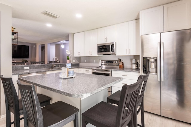 4132 Festival Pointe Blvd, Mulberry, FL 33860 - kitchen with stainless steel appliances, a breakfast bar, a center island, white cabinets, and recessed lighting