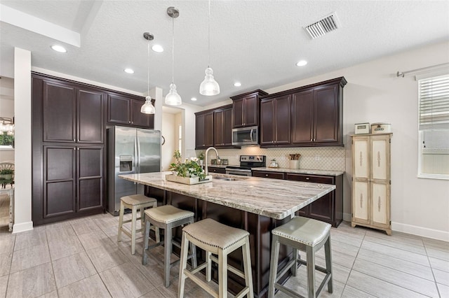 1237 Windy Bay Shl, Tarpon Springs, FL 34689 - kitchen with appliances with stainless steel finishes, dark brown cabinetry, tasteful backsplash, a breakfast bar, and recessed lighting