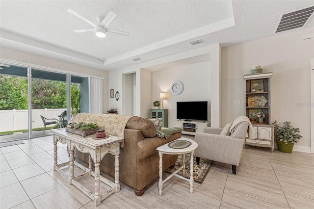 1237 Windy Bay Shl, Tarpon Springs, FL 34689 - living area featuring light tile patterned floors, a textured ceiling, a ceiling fan, and a tray ceiling