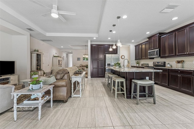 1237 Windy Bay Shl, Tarpon Springs, FL 34689 - kitchen with stainless steel appliances, open floor plan, a breakfast bar, ceiling fan, and dark brown cabinetry