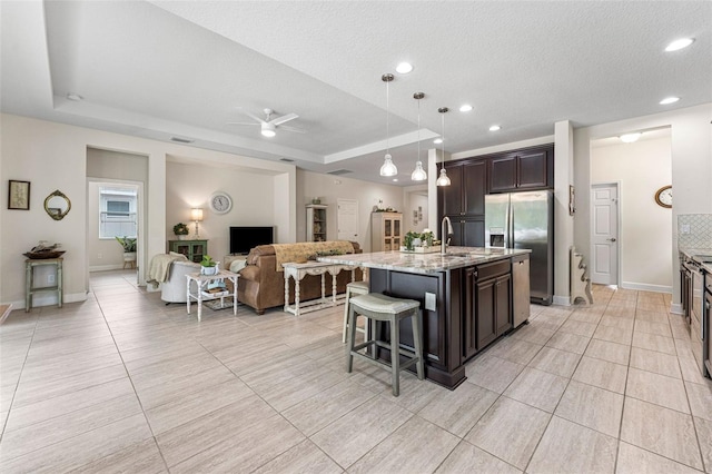 1237 Windy Bay Shl, Tarpon Springs, FL 34689 - kitchen with stainless steel appliances, a tray ceiling, open floor plan, ceiling fan, and dark brown cabinets