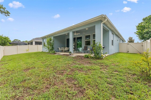 1237 Windy Bay Shl, Tarpon Springs, FL 34689 - back of property featuring a gate, stucco siding, a fenced backyard, ceiling fan, and a patio area