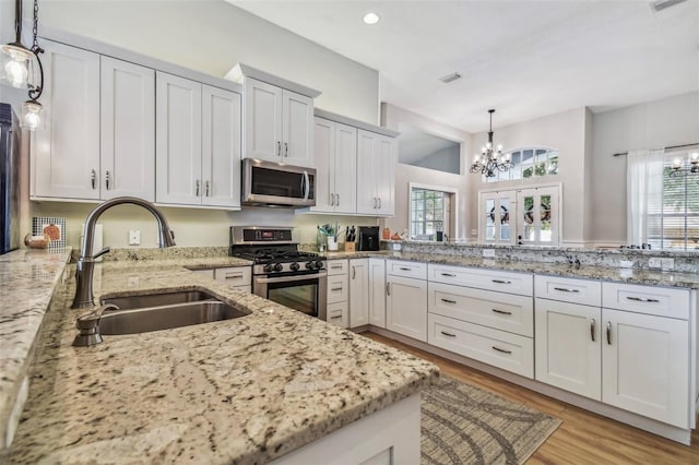 6804 Pleasant Oaks Pl, Riverview, FL 33578 - kitchen with stainless steel appliances, a chandelier, light stone counters, light wood finished floors, and decorative light fixtures