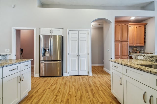 6804 Pleasant Oaks Pl, Riverview, FL 33578 - kitchen featuring stainless steel fridge, arched walkways, light wood-style floors, and light stone countertops