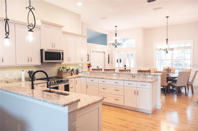 6804 Pleasant Oaks Pl, Riverview, FL 33578 - kitchen featuring stainless steel microwave, a peninsula, a chandelier, light wood finished floors, and light stone counters