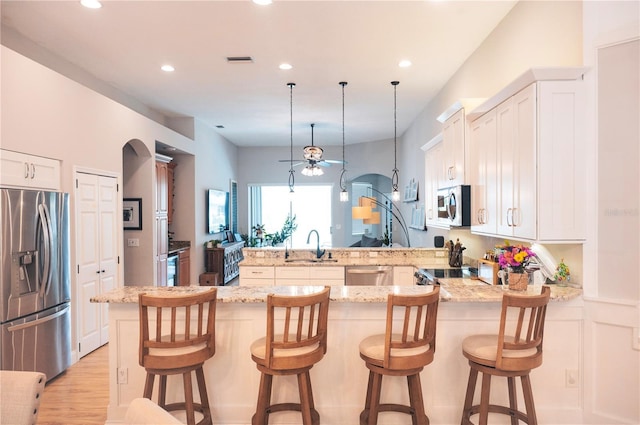 6804 Pleasant Oaks Pl, Riverview, FL 33578 - kitchen with stainless steel appliances, a peninsula, light stone counters, recessed lighting, and white cabinets