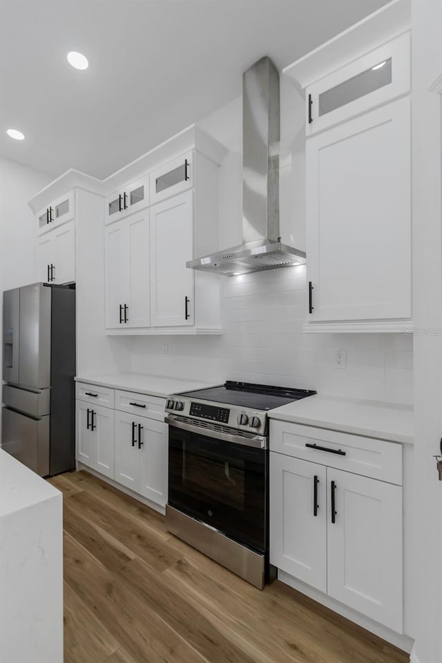 1213 E Lemon St, Tarpon Springs, FL 34689 - kitchen with appliances with stainless steel finishes, wall chimney range hood, light wood-style floors, white cabinets, and glass insert cabinets
