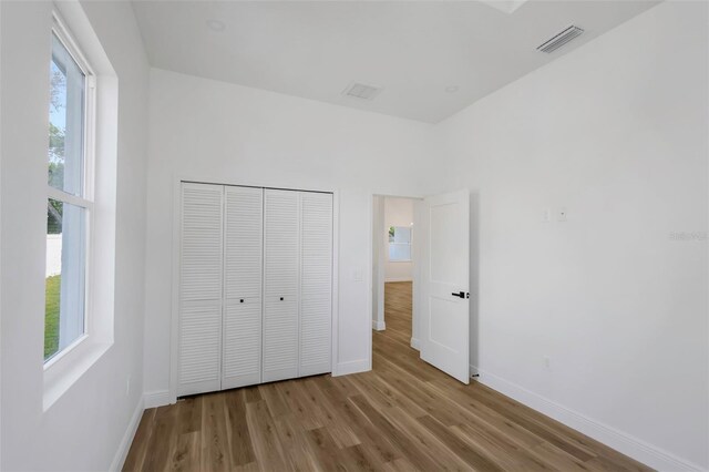 1213 E Lemon St, Tarpon Springs, FL 34689 - unfurnished bedroom with wood finished floors, multiple windows, and a closet