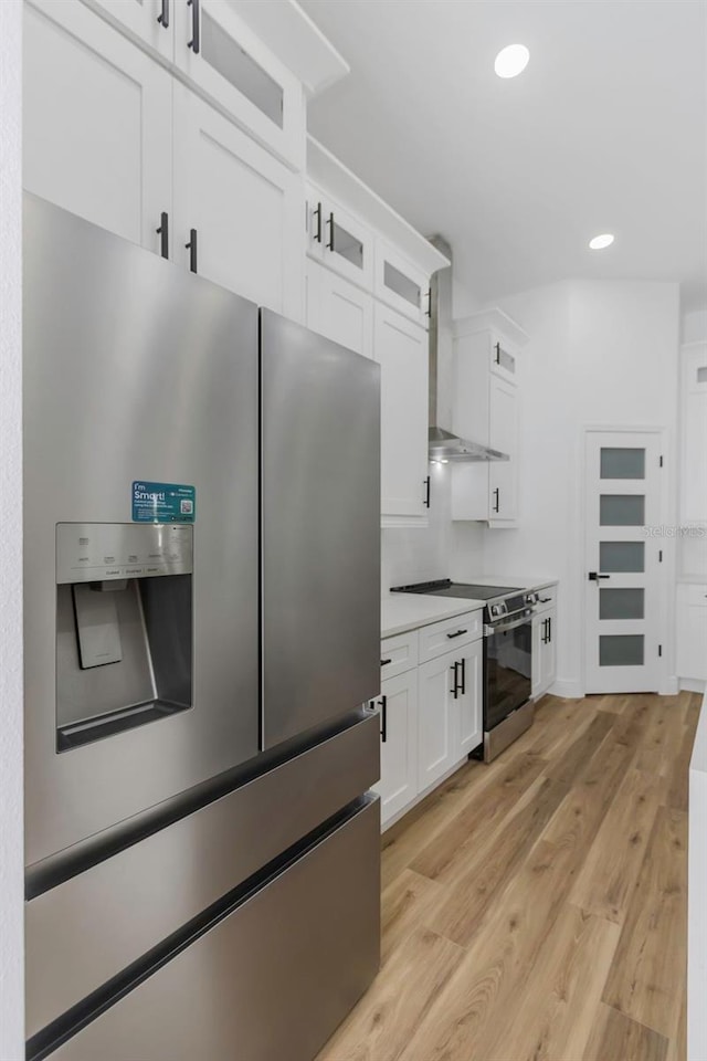 1213 E Lemon St, Tarpon Springs, FL 34689 - kitchen with stainless steel appliances, wall chimney exhaust hood, light wood-type flooring, white cabinetry, and recessed lighting