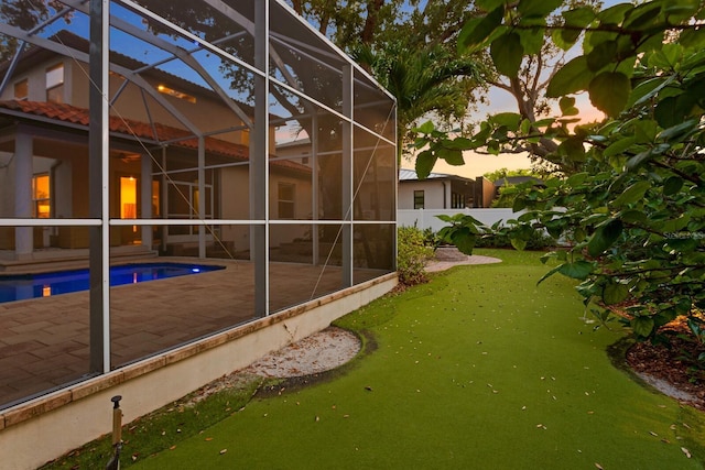 3307 W Knights Ave, Tampa, FL 33611 - property exterior at dusk with glass enclosure, a patio area, an outdoor pool, and stucco siding