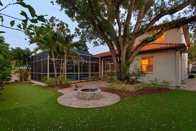 3307 W Knights Ave, Tampa, FL 33611 - rear view of house featuring a tiled roof, a fire pit, a lawn, stucco siding, and a patio area
