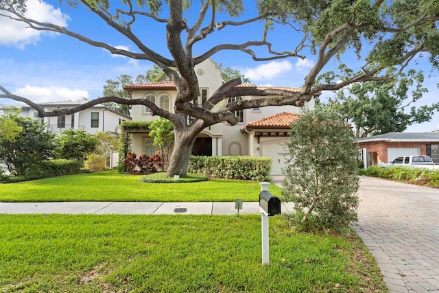 3307 W Knights Ave, Tampa, FL 33611 - mediterranean / spanish house featuring a tile roof, decorative driveway, stucco siding, a garage, and a front yard