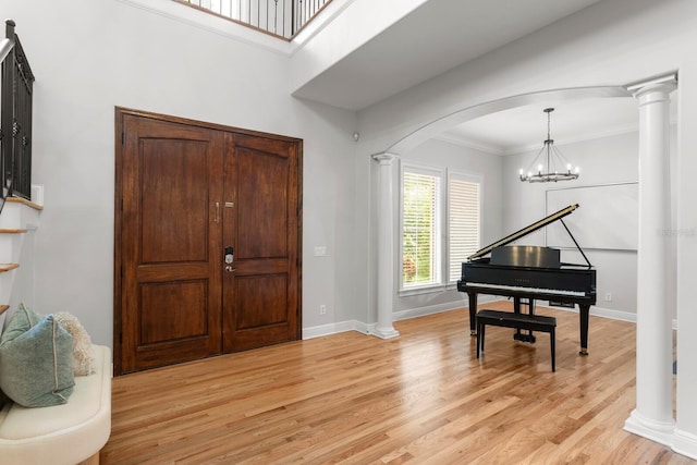 3307 W Knights Ave, Tampa, FL 33611 - foyer entrance with light wood-type flooring, arched walkways, a chandelier, ornamental molding, and decorative columns