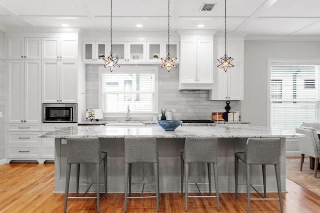3307 W Knights Ave, Tampa, FL 33611 - kitchen with a kitchen breakfast bar, white cabinetry, stainless steel microwave, backsplash, and recessed lighting