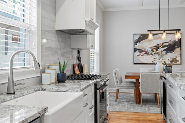 3307 W Knights Ave, Tampa, FL 33611 - kitchen with high end stainless steel range, crown molding, custom range hood, white cabinetry, and tasteful backsplash