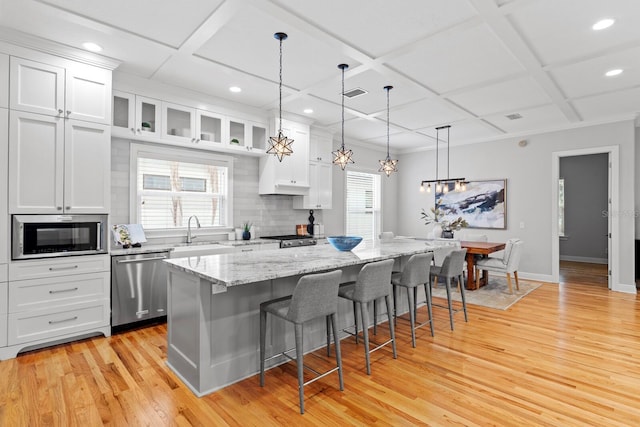 3307 W Knights Ave, Tampa, FL 33611 - kitchen featuring appliances with stainless steel finishes, coffered ceiling, a kitchen bar, light wood-type flooring, and white cabinetry