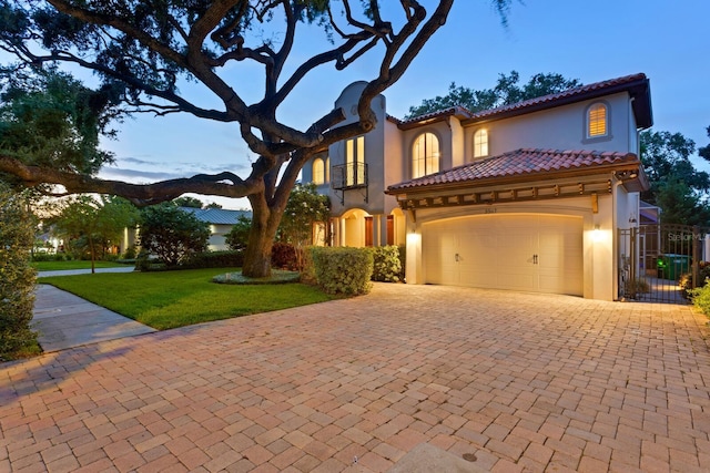 3307 W Knights Ave, Tampa, FL 33611 - mediterranean / spanish house featuring stucco siding, decorative driveway, a tiled roof, an attached garage, and a gate