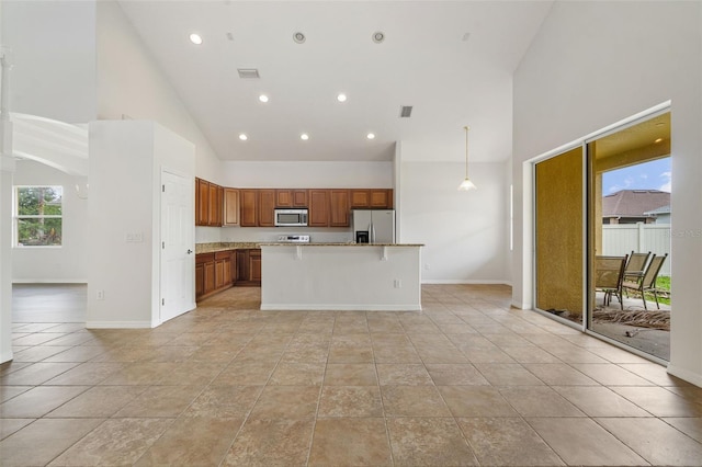 3013 Silvermill Loop Unit O, Land O Lakes, FL 34638 - kitchen with stainless steel appliances, high vaulted ceiling, brown cabinets, a center island, and recessed lighting