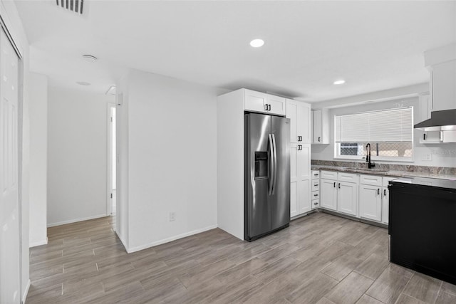 4535 15th Ave S, Saint Petersburg, FL 33711 - kitchen with stainless steel fridge, light wood finished floors, white cabinetry, and recessed lighting
