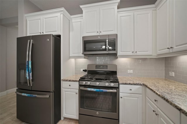 6408 Seasound Dr, Apollo Beach, FL 33572 - kitchen with stainless steel appliances, white cabinetry, and decorative backsplash