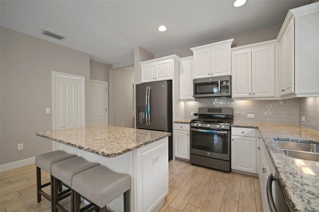6408 Seasound Dr, Apollo Beach, FL 33572 - kitchen with appliances with stainless steel finishes, light wood-style floors, a center island, decorative backsplash, and recessed lighting