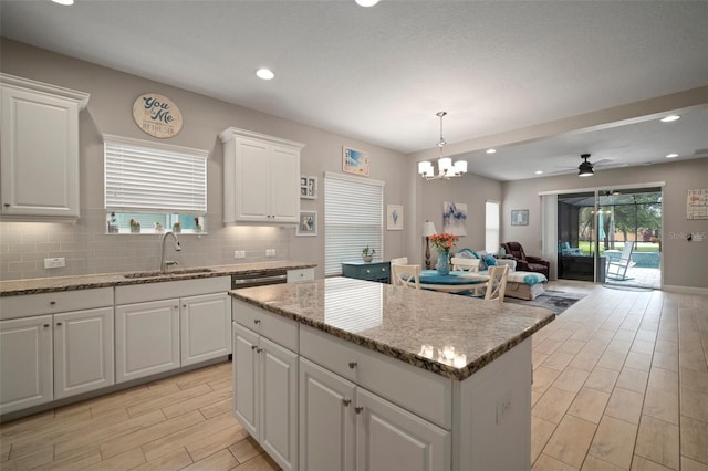 6408 Seasound Dr, Apollo Beach, FL 33572 - kitchen with a kitchen island, ceiling fan, open floor plan, decorative backsplash, and white cabinetry