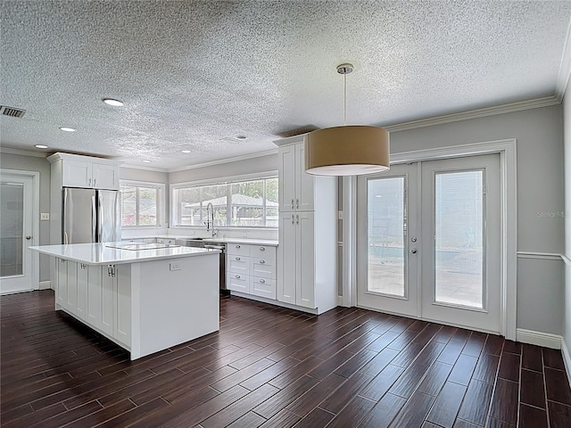 4002 Hudson Ter, Tampa, FL 33618 - kitchen featuring appliances with stainless steel finishes, a textured ceiling, light countertops, a center island, and white cabinets