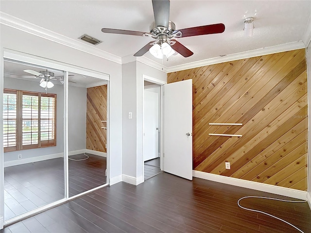 4002 Hudson Ter, Tampa, FL 33618 - unfurnished bedroom featuring wooden walls, crown molding, wood finished floors, ceiling fan, and a closet