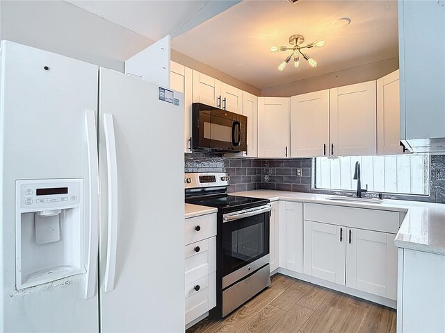4002 Hudson Ter, Tampa, FL 33618 - kitchen featuring white fridge with ice dispenser, black microwave, stainless steel range with electric cooktop, light wood-style flooring, and white cabinets