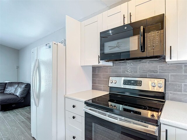 4002 Hudson Ter, Tampa, FL 33618 - kitchen with stainless steel electric range oven, freestanding refrigerator, black microwave, white cabinets, and decorative backsplash