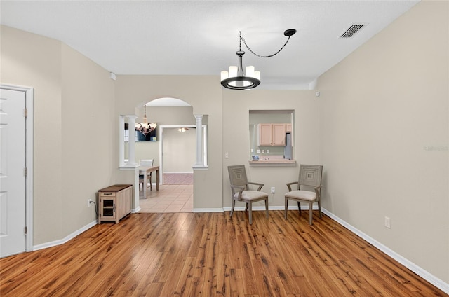 1822 Sassafras Dr, Wesley Chapel, FL 33543 - dining space with arched walkways, a chandelier, wood finished floors, and decorative columns