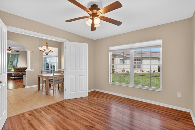 1822 Sassafras Dr, Wesley Chapel, FL 33543 - empty room featuring a ceiling fan, decorative columns, light wood-style flooring, and a chandelier
