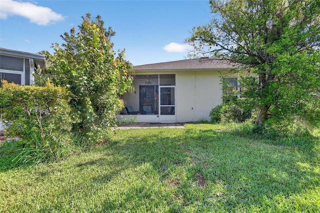 1822 Sassafras Dr, Wesley Chapel, FL 33543 - rear view of property with stucco siding, a sunroom, and a lawn