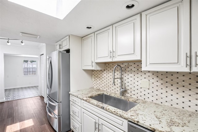 6220 Murdock Ave, Sarasota, FL 34231 - kitchen featuring freestanding refrigerator, white cabinets, dark wood-style flooring, backsplash, and a skylight