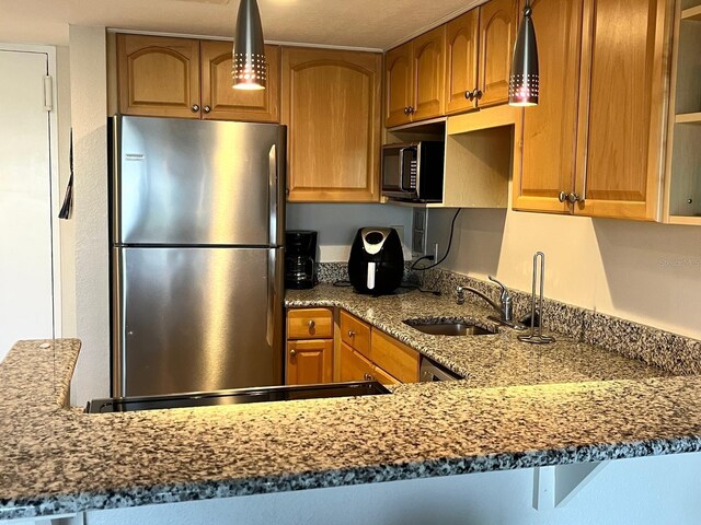 880 Mandalay Ave Unit C412, Clearwater Beach, FL 33767 - kitchen featuring freestanding refrigerator, black microwave, brown cabinetry, and dark stone countertops