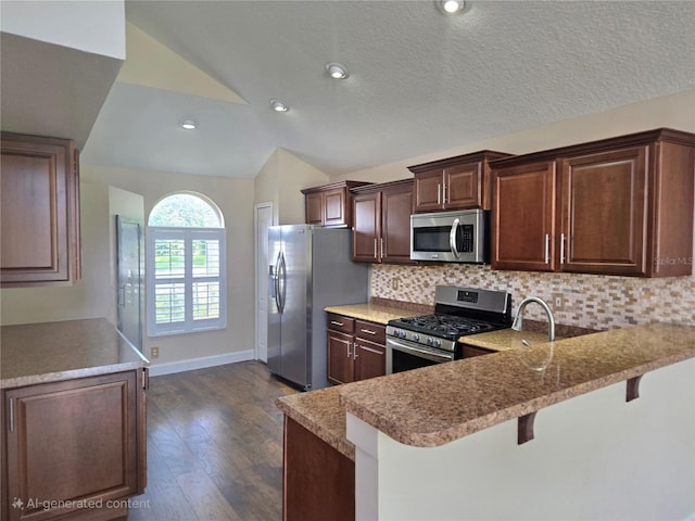 31141 Harthorn Ct, Wesley Chapel, FL 33543 - kitchen featuring appliances with stainless steel finishes, lofted ceiling, dark wood-style flooring, decorative backsplash, and a kitchen breakfast bar