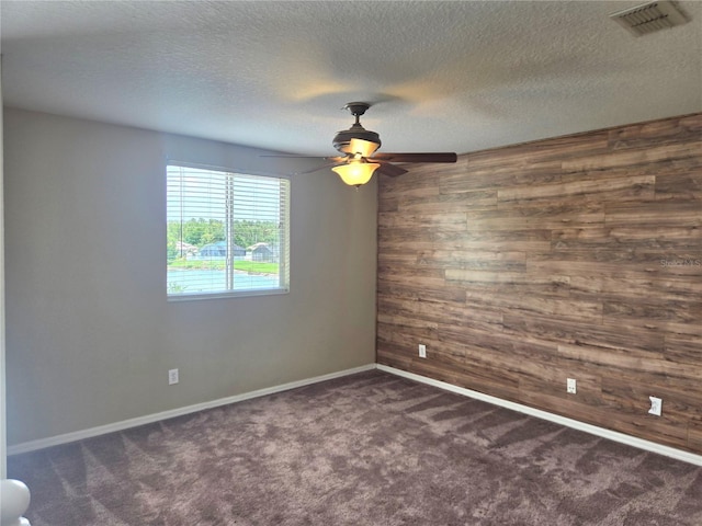 31141 Harthorn Ct, Wesley Chapel, FL 33543 - empty room with wooden walls, ceiling fan, dark carpet, and a textured ceiling