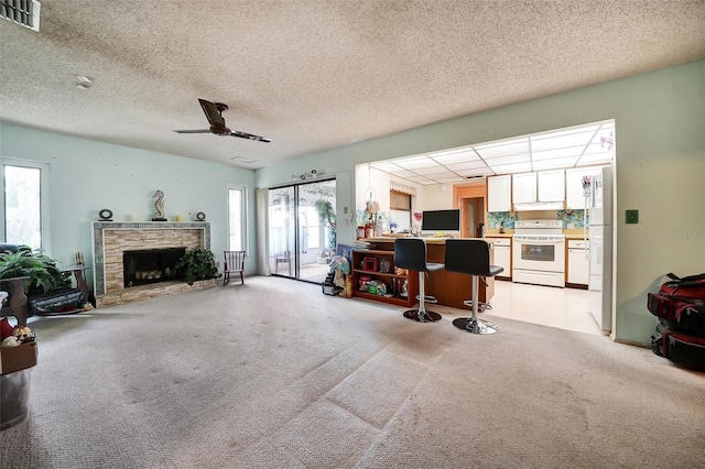 2817 Rustic Oaks Dr, Palm Harbor, FL 34684 - living room with a textured ceiling, light colored carpet, a stone fireplace, and a ceiling fan