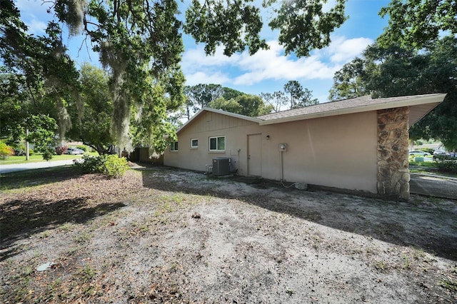 2817 Rustic Oaks Dr, Palm Harbor, FL 34684 - view of side of home with a central AC unit and stone siding