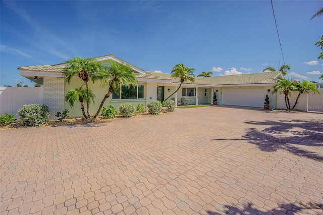 5950 Bikini Way N, St Pete Beach, FL 33706 - ranch-style home featuring decorative driveway, a tiled roof, an attached garage, and brick siding