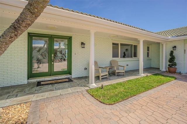 5950 Bikini Way N, St Pete Beach, FL 33706 - view of exterior entry with brick siding, french doors, and a tile roof