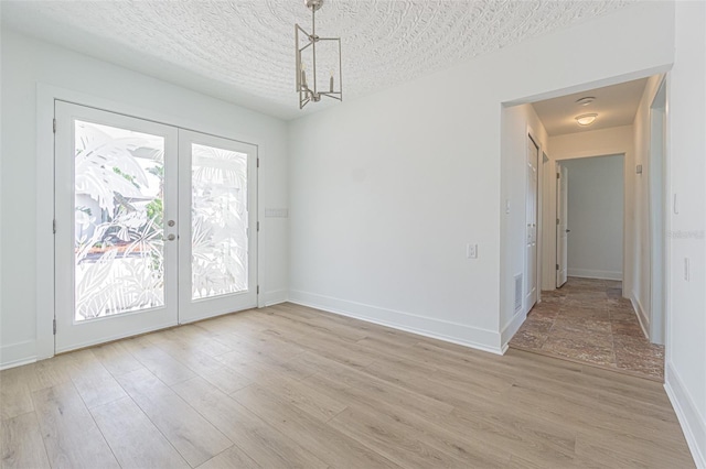 5950 Bikini Way N, St Pete Beach, FL 33706 - unfurnished dining area featuring french doors, light wood finished floors, and a chandelier