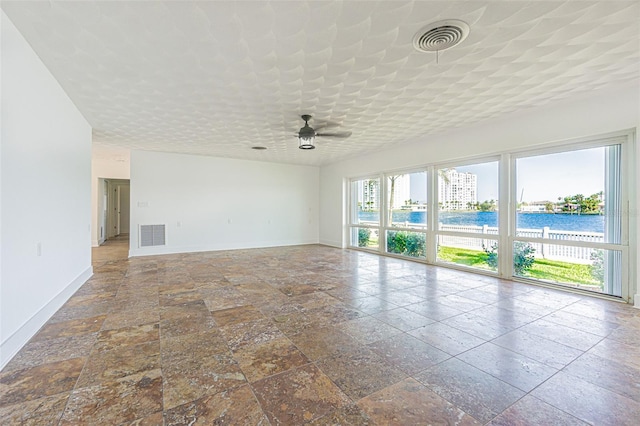 5950 Bikini Way N, St Pete Beach, FL 33706 - unfurnished room featuring stone tile flooring, a ceiling fan, and a water view