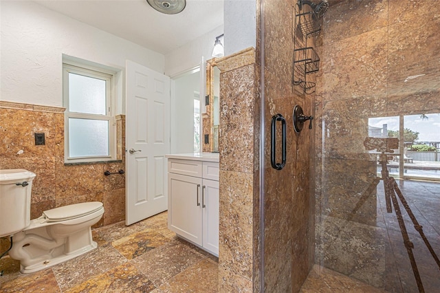 5950 Bikini Way N, St Pete Beach, FL 33706 - full bath with a stall shower, tile walls, vanity, a wainscoted wall, and stone tile floors