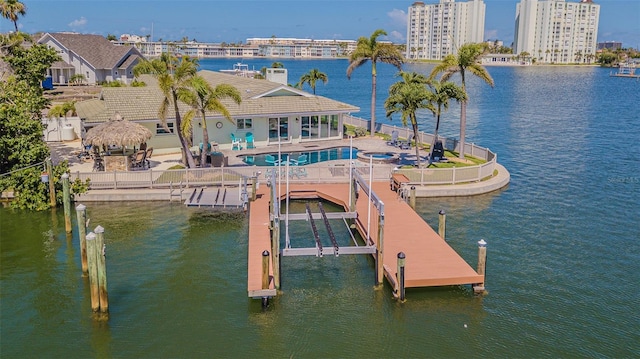 5950 Bikini Way N, St Pete Beach, FL 33706 - dock with boat lift, a community pool, a patio area, a water view, and a fenced backyard