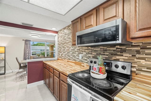 6715 Ranchwood Loop, New Port Richey, FL 34653 - kitchen featuring stainless steel appliances, butcher block countertops, decorative backsplash, and brown cabinets