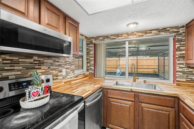 6715 Ranchwood Loop, New Port Richey, FL 34653 - kitchen with stainless steel appliances, wood counters, tasteful backsplash, brown cabinetry, and a textured ceiling