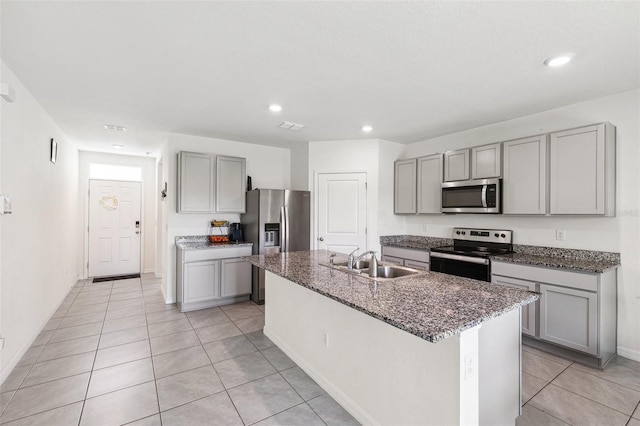 33657 Field Maple Loop, Wesley Chapel, FL 33545 - kitchen with stainless steel appliances, gray cabinetry, light tile patterned floors, recessed lighting, and dark stone countertops